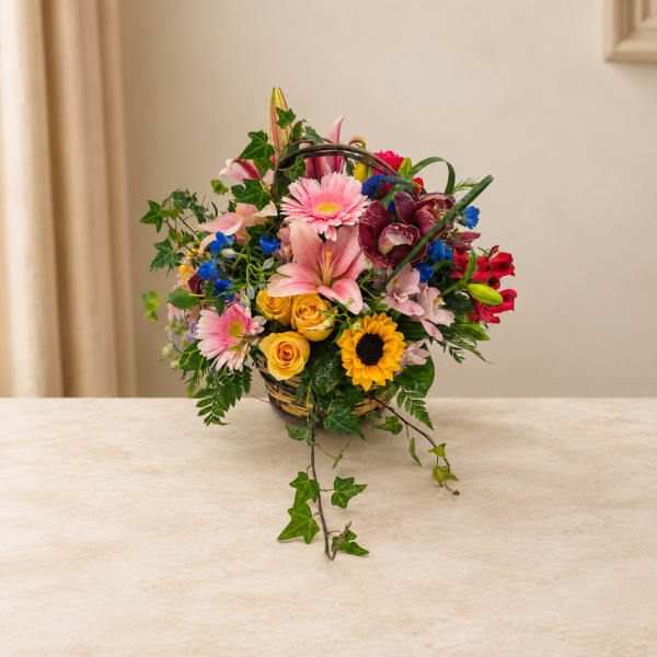 Mixed bouquet in a woven basket with pink, yellow, red, and blue flowers