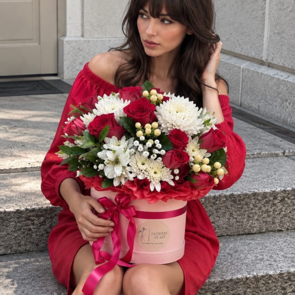 Woman holding a pink hatbox of red and white flowers