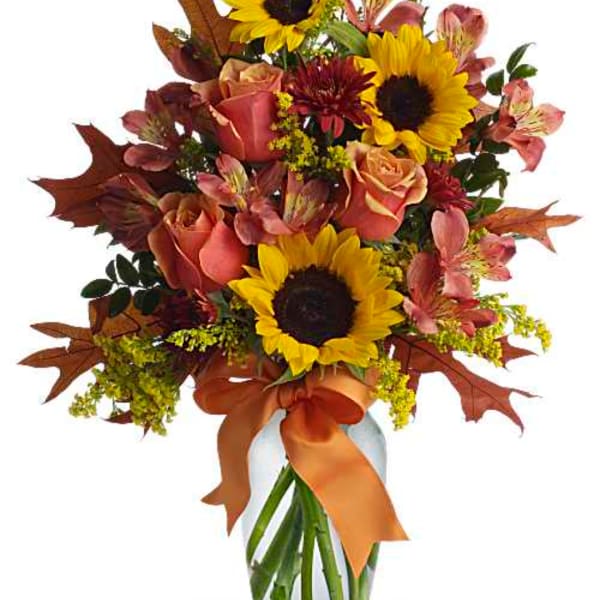 Bouquet of sunflowers, roses, and alstroemeria in a vase with an orange ribbon