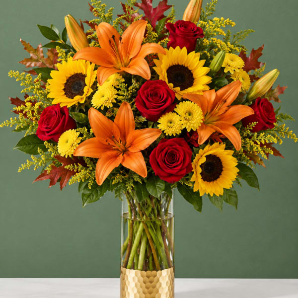 Bouquet of sunflowers, red roses, and orange lilies in a glass vase