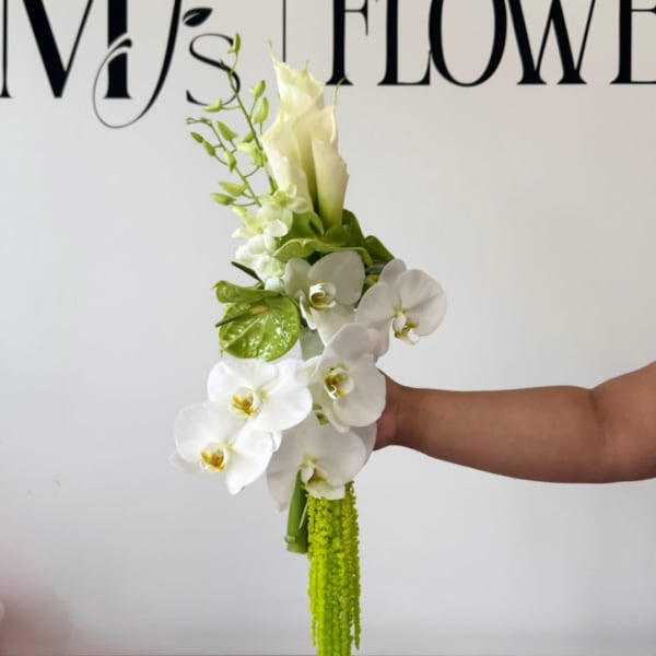 White orchid bouquet with green accents held in a hand