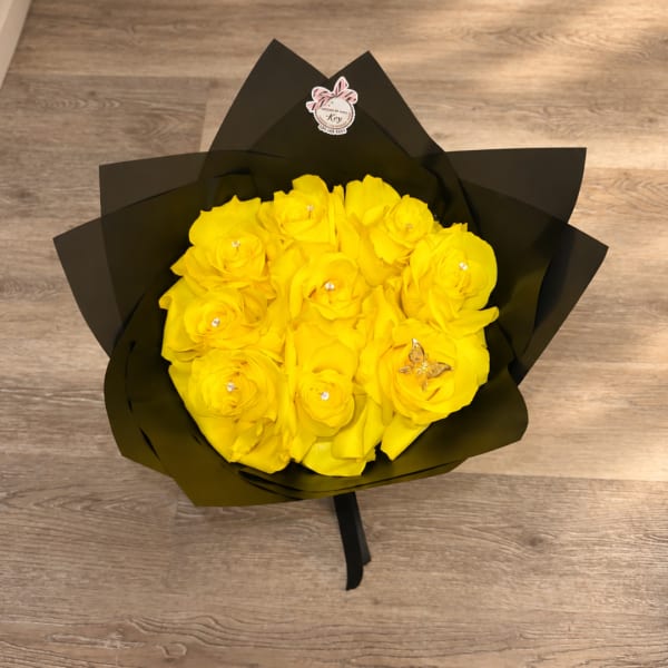 Yellow rose bouquet wrapped in black paper on a wood floor