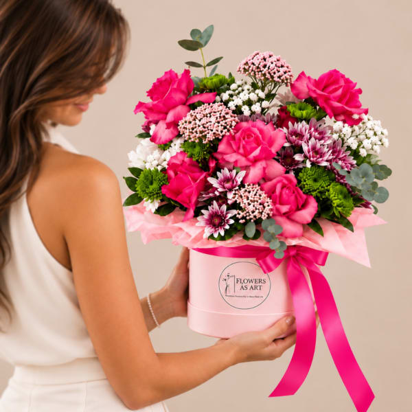 Woman holding a pink hatbox arrangement of bright pink roses and mixed flowers