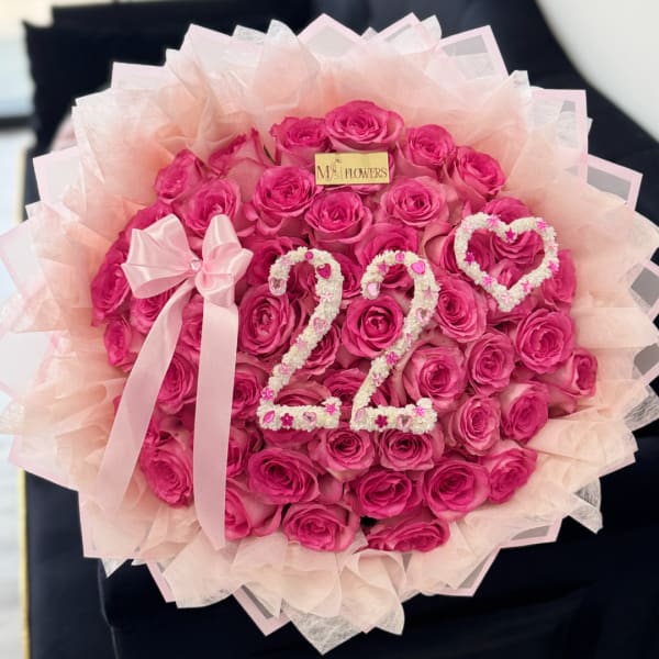 Round bouquet of bright pink roses with a pale pink ribbon and decorative number 22