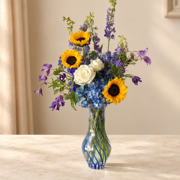 Sunflowers, white roses, and blue flowers in a striped glass vase