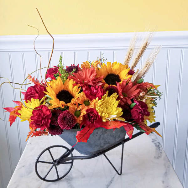 Colorful fall flower arrangement in a wheelbarrow-shaped container