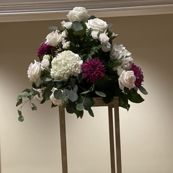 White and purple floral arrangement on a tall stand