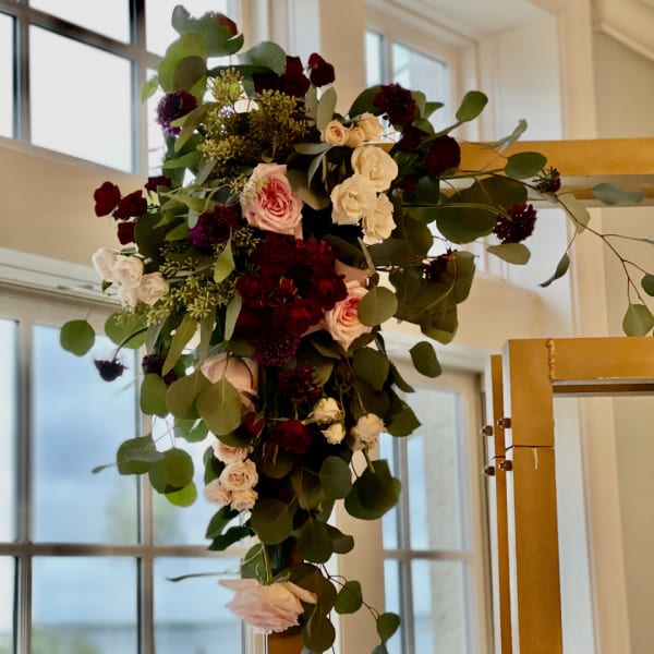 Tall floral arrangement with pink and white roses and dark burgundy blooms