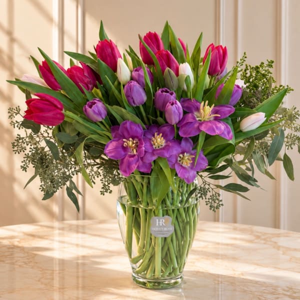 Bouquet of pink and purple tulips in a clear glass vase