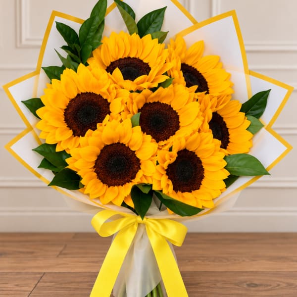 Bouquet of yellow sunflowers wrapped in white paper with a yellow ribbon