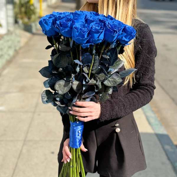 Woman holding a large bouquet of vivid blue roses