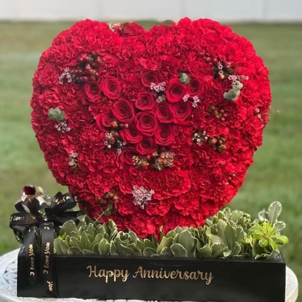 Heart-shaped red rose and carnation arrangement in a black box with anniversary text