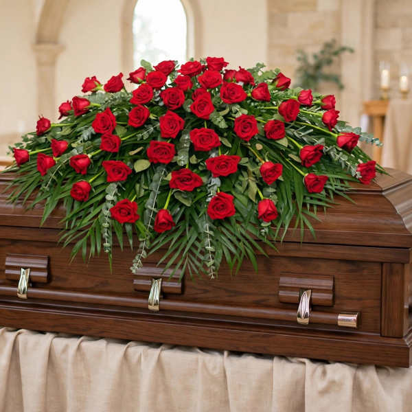 Red rose casket spray on a wooden coffin in a church