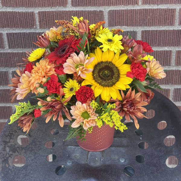 Mixed bouquet with sunflowers, daisies, and carnations in a pink vase