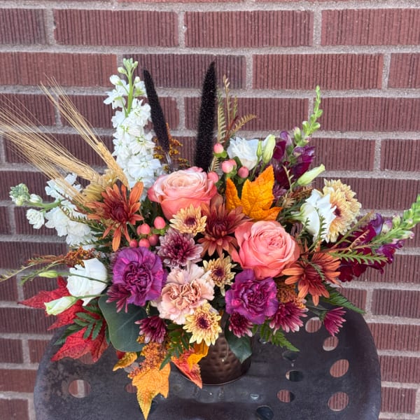 Autumn bouquet with pink roses, chrysanthemums, and white blooms in a dark vase