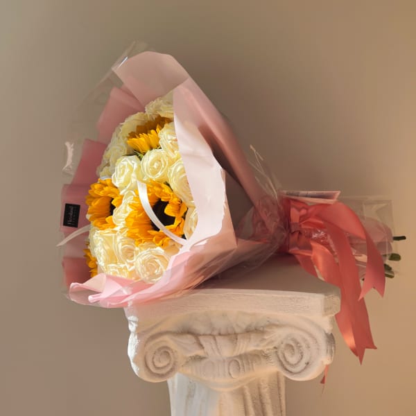 Bouquet of white roses and yellow sunflowers wrapped in pink paper