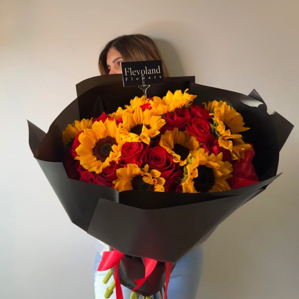 Bouquet of red roses and yellow sunflowers wrapped in black paper