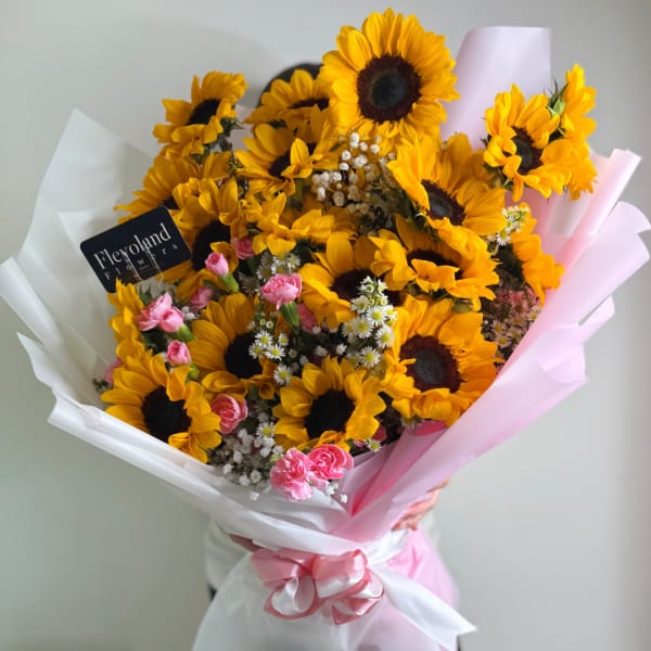 Bouquet of sunflowers with pink carnations wrapped in white and pink paper