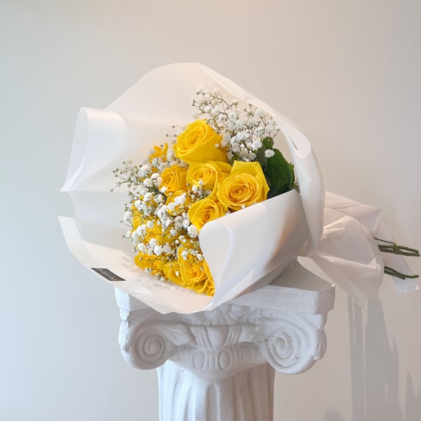 Yellow roses wrapped in white paper with baby's breath
