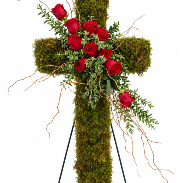 Red roses arranged on a moss-covered cross with trailing branches