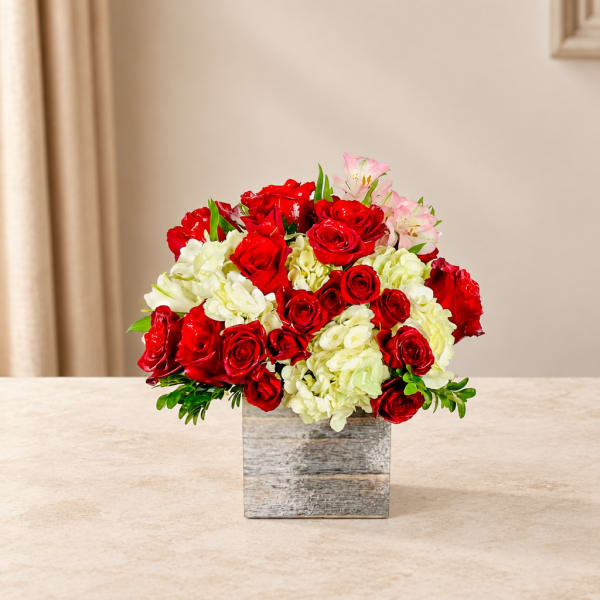 Red roses and white hydrangeas in a square vase with pink lilies