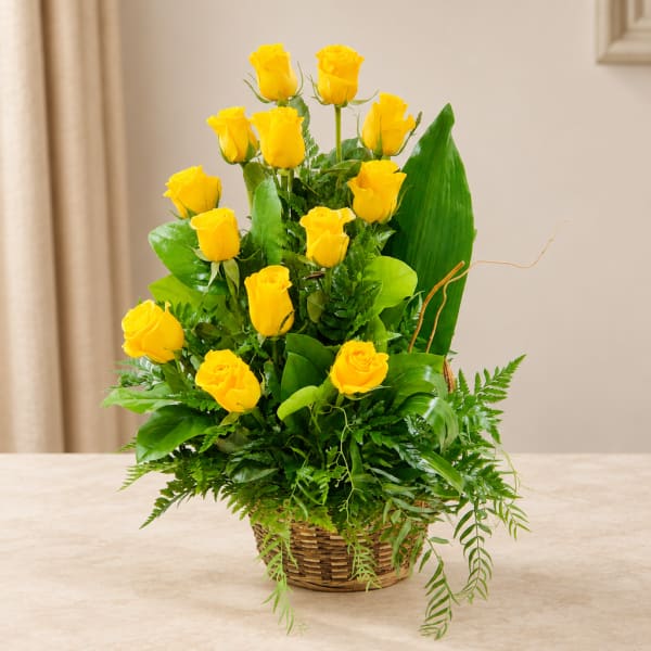Yellow roses arranged in a wicker basket with greenery