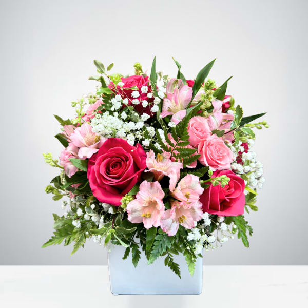 Pink roses and alstroemeria in a square glass vase