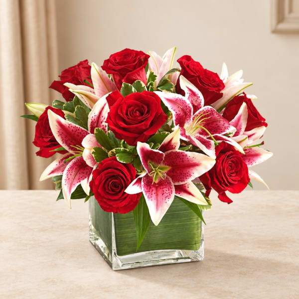 Red roses and pink lilies arranged in a square glass vase