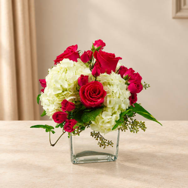 Pink roses and white hydrangeas arranged in a clear glass vase