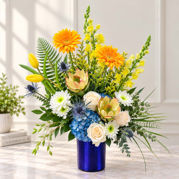 Bright mixed bouquet in a blue vase with yellow, white, and blue flowers