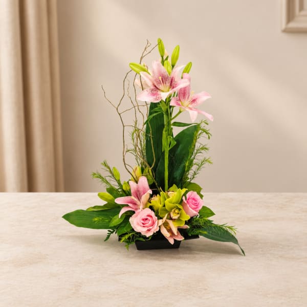 Pink lilies and roses in a low black container