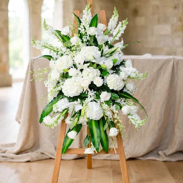 White floral standing arrangement on a wooden easel