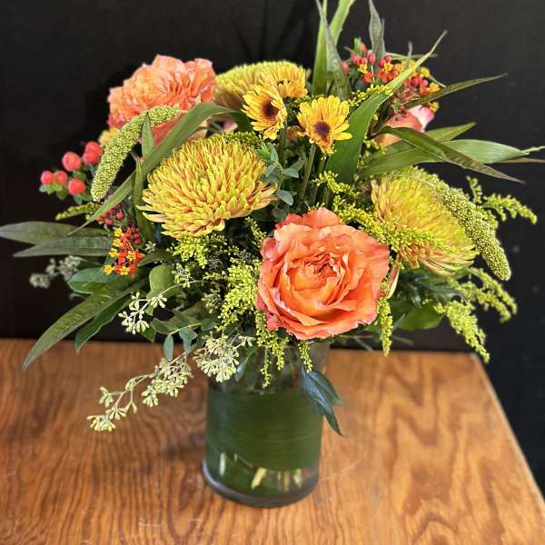 Orange roses and yellow chrysanthemums in a glass vase