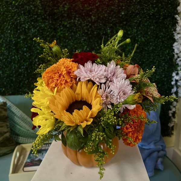 Mixed bouquet in a pumpkin-shaped vase with sunflowers and mums