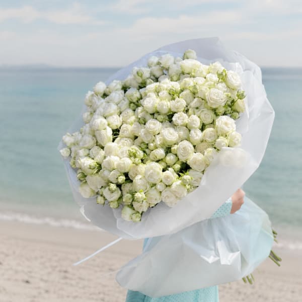 Large bouquet of white roses wrapped in translucent paper