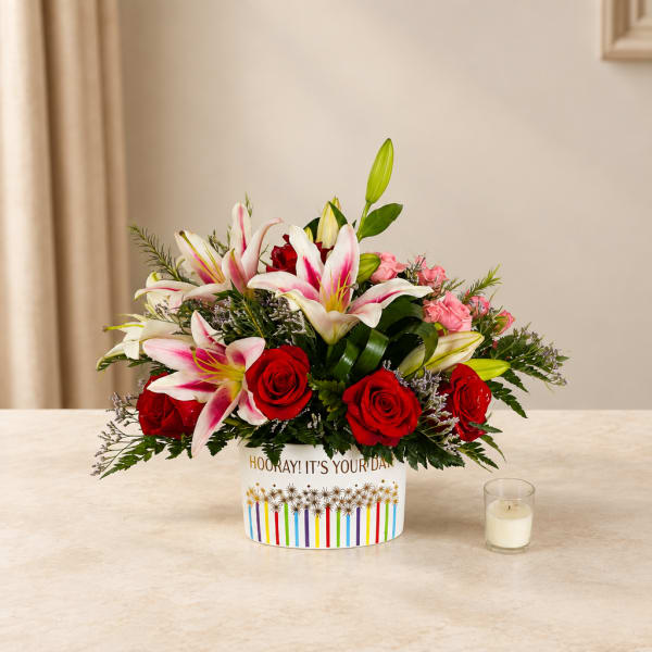 Red roses and pink lilies in a printed container on a table