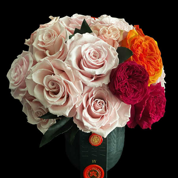 Bouquet of pale pink and bright orange roses in a dark wrap