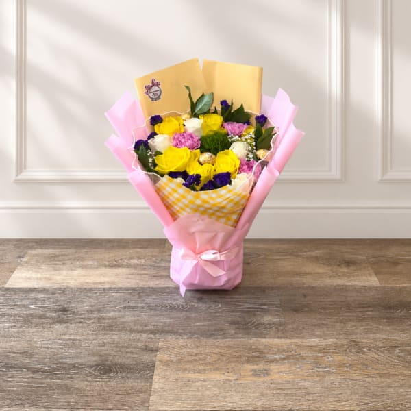Bouquet of yellow, pink, and white roses wrapped in pink paper