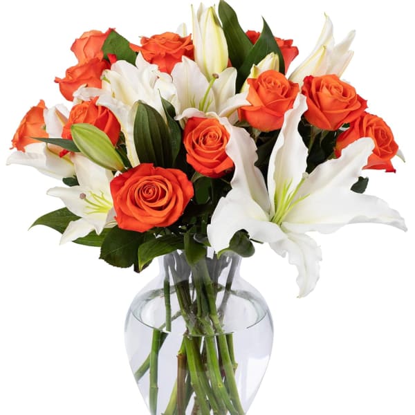 Orange roses and white lilies in a clear glass vase