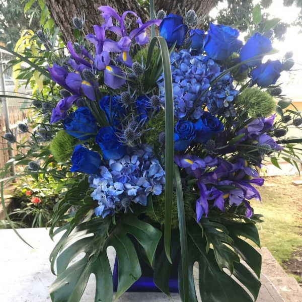 Blue and purple floral arrangement with roses, hydrangeas, and irises