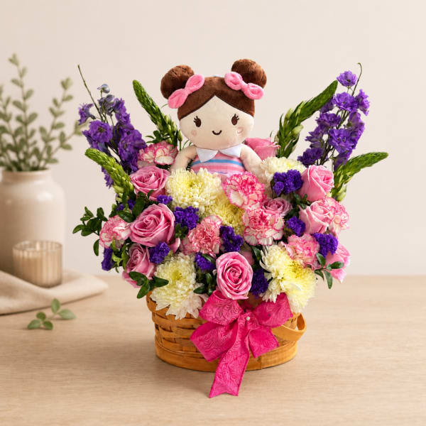 Basket arrangement with a doll surrounded by pink, purple, and white flowers