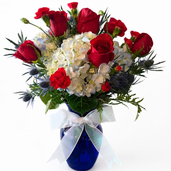 Red roses and white hydrangeas in a blue vase with a white ribbon