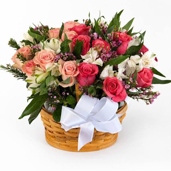 Mixed pink and white roses in a wicker basket with a white ribbon