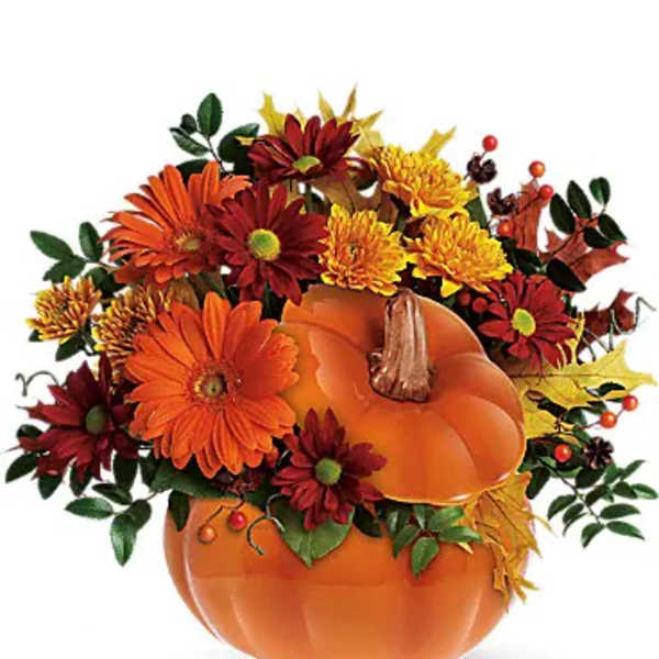 Autumn floral arrangement in a pumpkin-shaped container with orange and red blooms