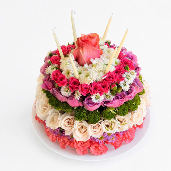 Round floral cake with pink and white roses and candles