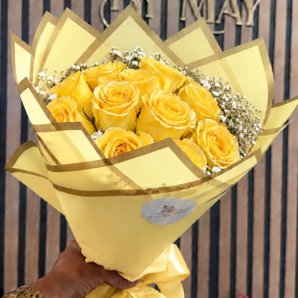Yellow rose bouquet wrapped in pale yellow paper with a satin ribbon