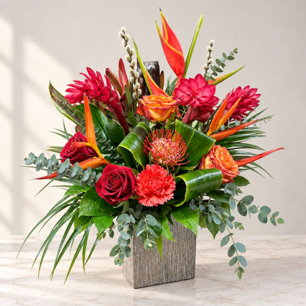 Tropical bouquet with red and orange flowers in a textured square vase