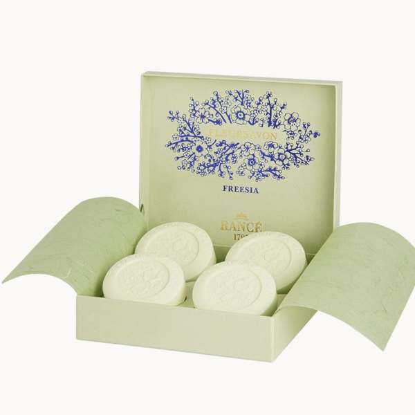 Open gift box with round white soaps and freesia branding