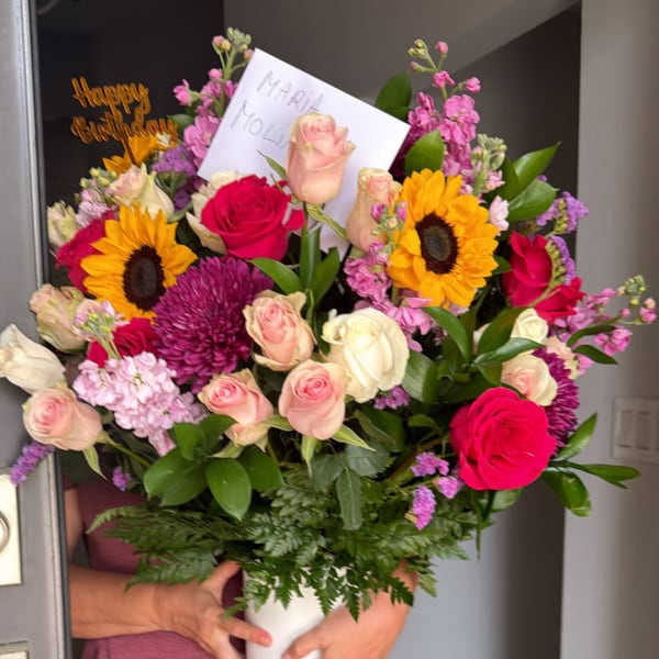 Mixed bouquet in a white vase with roses, sunflowers, and a birthday card