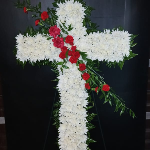 White floral cross with red flowers on a black stand